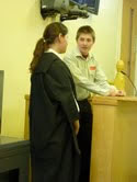 A witness takes the oath in the witness box with the help of the court usher during one of the trials