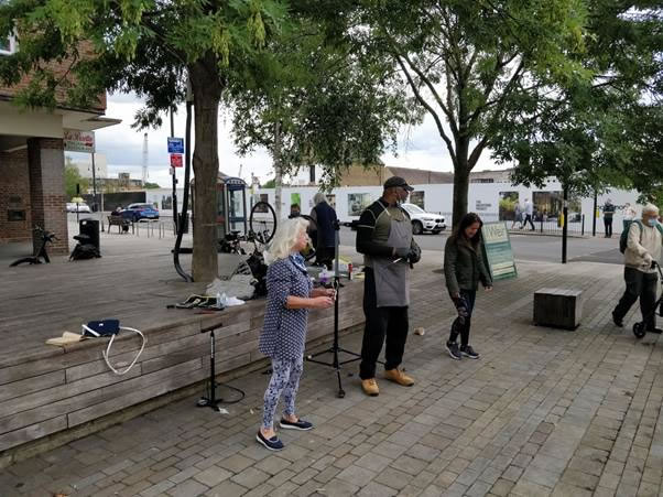 A group of people standing on a sidewalk  Description automatically generated