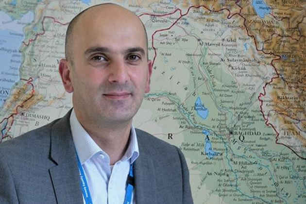 Hani Abdul-Jabar in front of a map of Iraq 